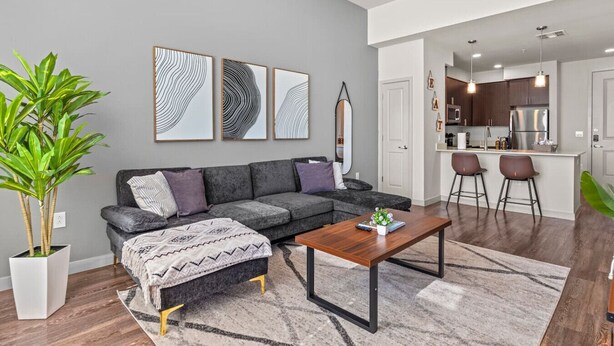 Ein modernes Wohnzimmer mit einem grauen Sofa, einem Couchtisch und einer großen Pflanze.