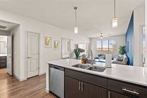 A modern kitchen with a dishwasher, double sink, and dark wood cabinets. - Tempe 2BR Escape - Pool, King Beds, Hot Tub, Gym (Tempe)