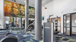 Ett gym med träningsutrustning, motiverande affischer och ett mönstrat golv.
