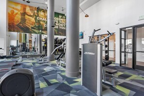 A gym with exercise equipment, motivational posters, and a patterned floor. - Tempe 2BR Escape | Pool, King Beds, Hot Tub, Gym (Tempe)