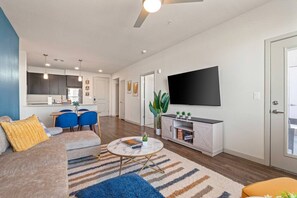 Una sala de estar moderna con un sofá, sillas, una mesa de centro y un televisor montado en la pared.