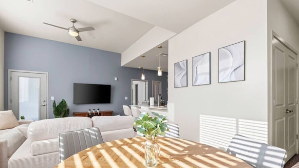 A modern living room with a round wooden table, a ceiling fan, a flat-screen TV, and a dining area with a white table and chairs. - 3BR Tempe Gem - Pool, King Beds, Gym, ASU Nearby (Tempe)