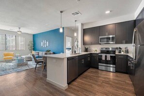 A modern kitchen with dark cabinetry, stainless steel appliances, and a central island. - Tempe's Finest - King Beds, Pool & Prime Location! (Tempe)