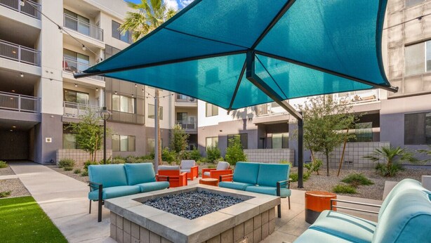 An outdoor seating area with a fire pit, lounge chairs, and a large umbrella. - Tempe`s Finest | King Beds, Pool & Prime Location! (Tempe)