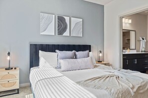 Un dormitorio con cama, mesitas de noche, cómoda y decoración en la pared.