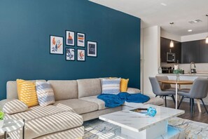 A modern living room with a sofa, coffee table, and artwork on the wall. - Tempe's Finest - King Beds, Pool & Prime Location! (Tempe)