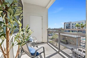 A balcony with a chair and a small table, overlooking a parking area and buildings. - Tempe's Finest - King Beds, Pool & Prime Location! (Tempe)