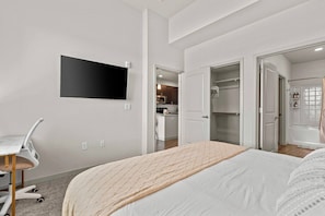 Ein modernes Hotelzimmer mit Bett, Schreibtisch, Fernseher und begehbarem Kleiderschrank.