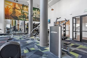 Un gimnasio con equipo de ejercicio, carteles motivacionales y suelo estampado.