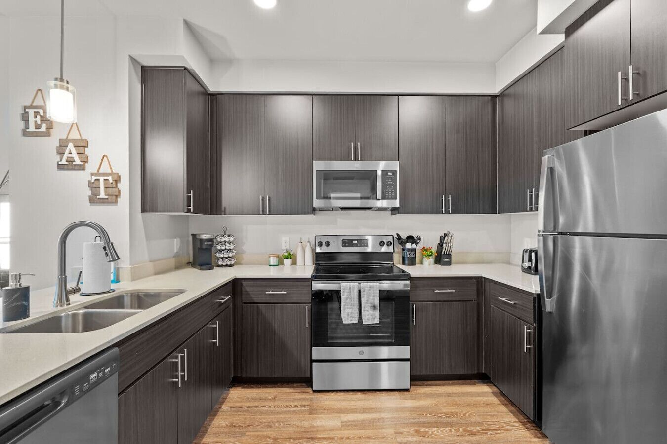 Una cocina moderna con armarios de madera oscura, electrodomésticos de acero inoxidable y piso de madera.