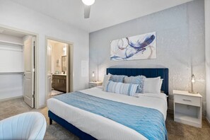 A bedroom with a large bed, bedside tables, a chair, and a bathroom visible through an open door. - Rest & Recover! | King Bed, Pool, Gym & More (Tempe)