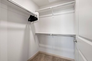 A walk-in closet with a single hanging rod and a shoe rack. - Rest & Recover - King Bed, Pool, Gym & More (Tempe)