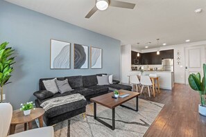 A modern living room with a sofa, coffee table, and artwork on the wall. - Tempe Oasis - King Beds, Pool, Gym, DT Tempe & ASU (Tempe)