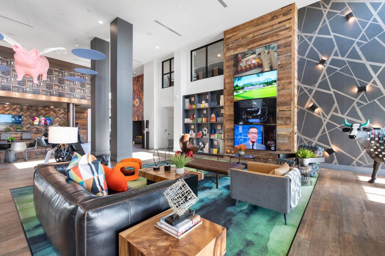 Eine moderne Hotelhalle mit Ledersofas, einem Couchtisch, einem an einer Holzwand montierten Fernseher und einer Bullskulptur.