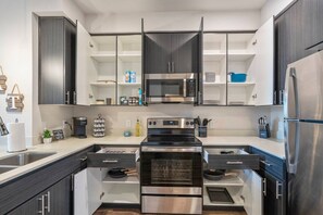 A modern kitchen with stainless steel appliances, open shelving, and a central island. - Luxury Tempe 1BR - Pool, Hot Tub, Gym, King Bed (Tempe)