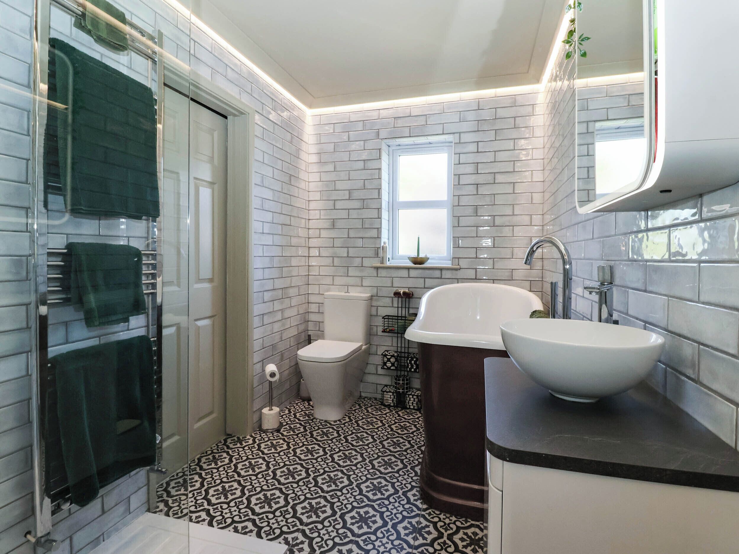 A bathroom with a glass shower enclosure, a toilet, a bathtub, and a sink.