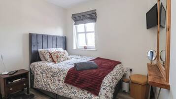 Une chambre à coucher comprenant un lit, une table de chevet, une commode, une fenêtre et un miroir.
