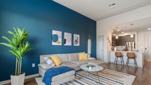 Ein modernes Wohnzimmer mit einer Couch, einem Couchtisch und einer großen Pflanze.