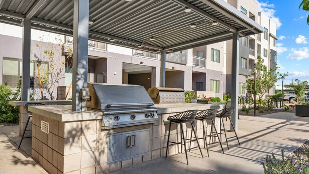 Ein Außenbereich mit Grill, Barhocker und überdachtem Sitzbereich.