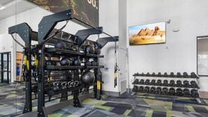 Uma academia com equipamentos de musculação, kettlebells e halteres.