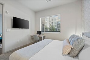 A bedroom with a bed, a desk with a computer, a television on the wall, and a window with blinds. - Luxury 2BR: King Beds, Pool - Near DT Tempe & ASU (Tempe)
