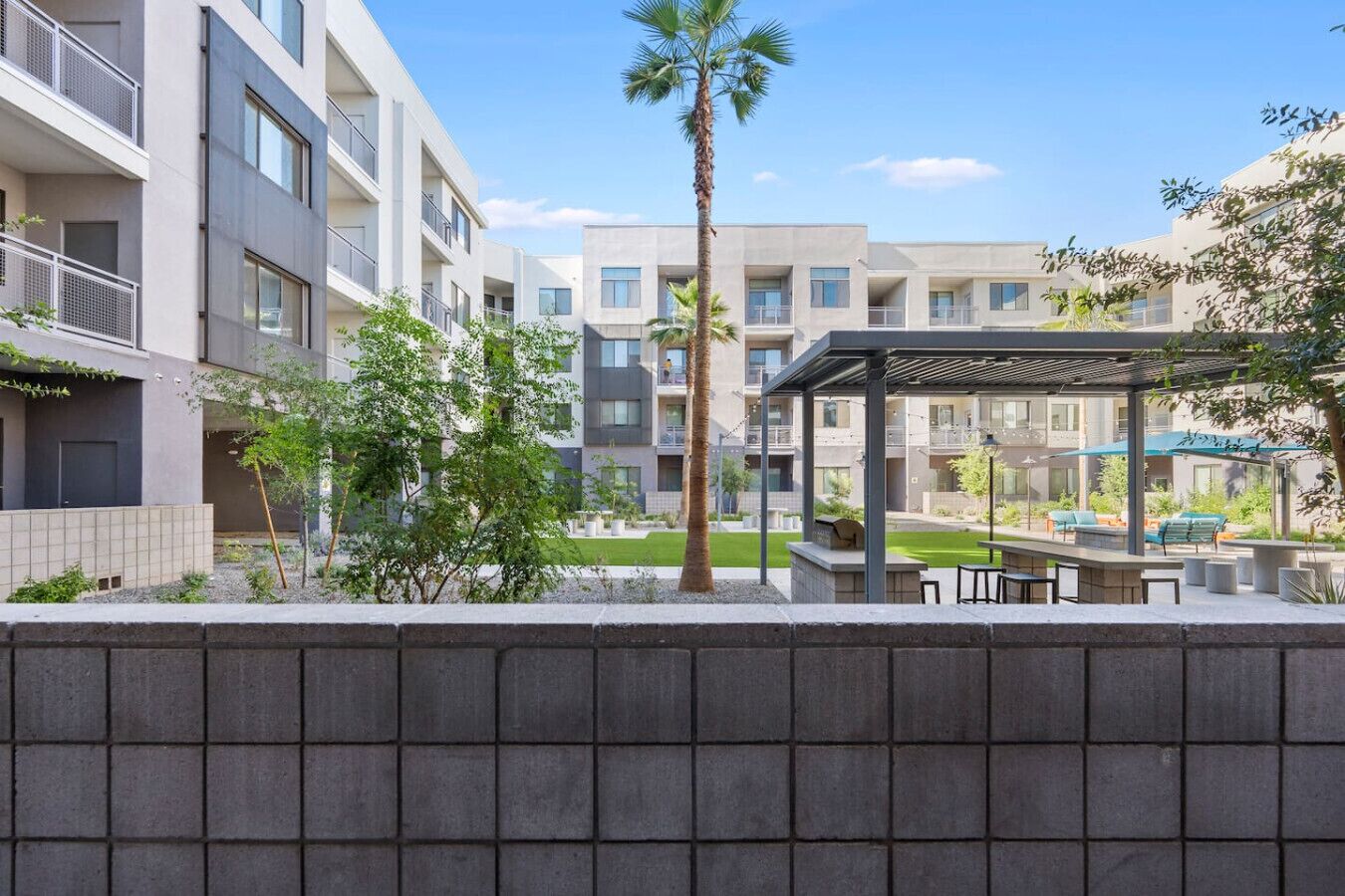 Een modern appartementencomplex met meerdere balkons, een overdekt terras en een goed onderhouden tuin.