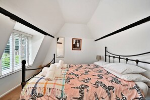 A bedroom with a bed, a window with blinds, a framed picture on the wall, and a mirror. - Welcoming Cottage in Kent Village (Tonbridge)