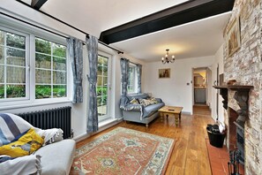 A cozy living room with a sofa, a coffee table, and a patterned rug. - Welcoming Cottage in Kent Village (Tonbridge)