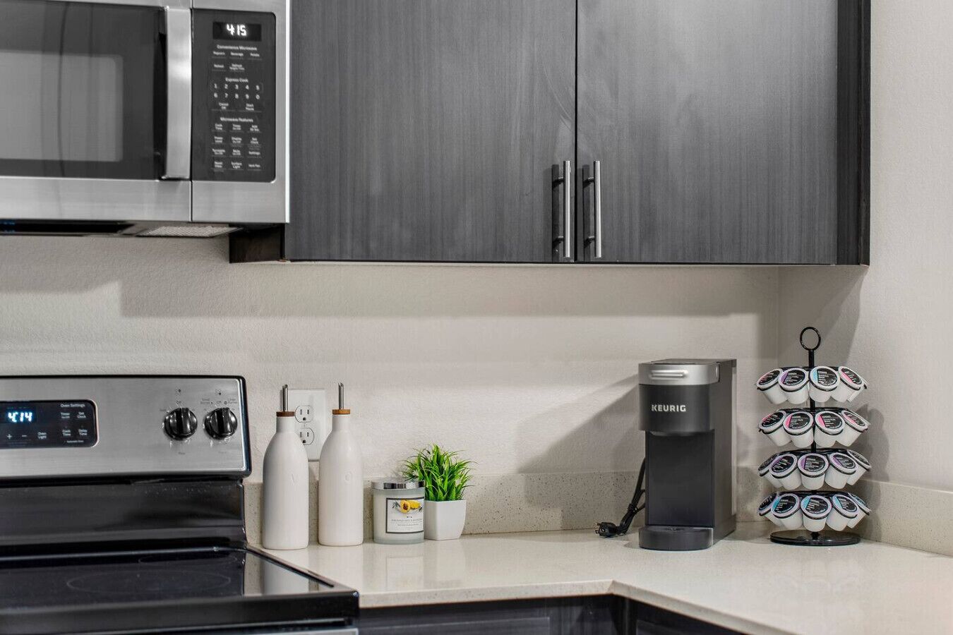 A kitchen with a microwave, coffee maker, and a coffee pod holder.