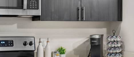 A kitchen with a microwave, coffee maker, and a coffee pod holder.
