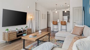 A modern living room with a flat-screen TV, wooden furniture, a coffee table, and a sofa. - Desert Oasis - Pool, Gym, Courtyard - King Bed (Tempe)