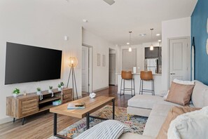Ein modernes Wohnzimmer mit Flachbildfernseher, Holzmöbeln, einem Couchtisch und einer Couch.