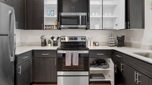 A modern kitchen with dark wood cabinets, stainless steel appliances, and white countertops. - Desert Oasis - Pool, Gym, Courtyard - King Bed (Tempe)