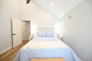 A bedroom with a bed, bedside tables, and a door. - Perfect 4-bedroom house located outside of the quaint town of Beaufort! (Beaufort)
