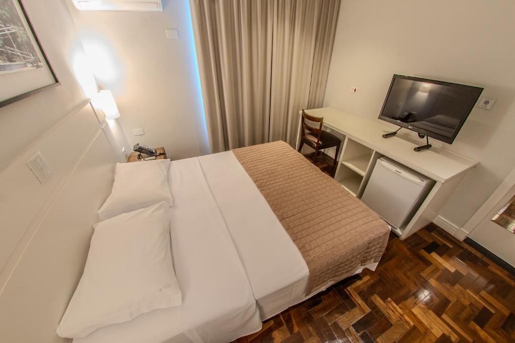 Ein Hotelzimmer mit Bett, Schreibtisch, Fernseher und Stuhl.