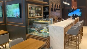 A modern bar area with a counter, seating, and a display case with various items. - Hotel Centro Europeu (Curitiba)