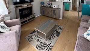 A modern living room with a flat-screen TV, a fireplace, a coffee table, and a sofa.