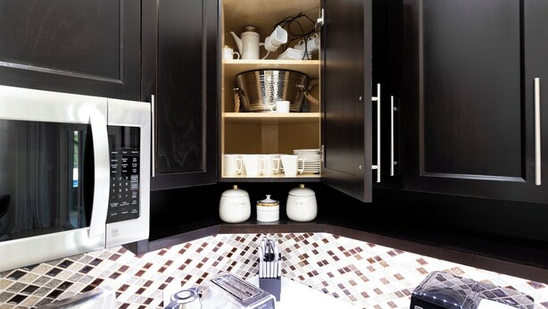 A modern kitchen with dark cabinetry, a built-in microwave, a coffee machine, and a tiled backsplash. - Luxury Villa Pool with Game Room Deerfield Beach (Pompano Beach)