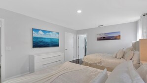 A bedroom with two beds, a white dresser, and two paintings on the walls. - Luxury Villa Pool with Game Room Deerfield Beach (Pompano Beach)