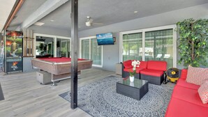 A modern living room with a pool table, red sofa, and a large window. - Luxury Villa Pool with Game Room Deerfield Beach (Pompano Beach)