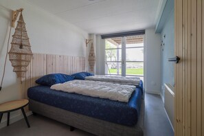 A bedroom with two beds, a hanging light fixture, and a view of the outdoors. - Beach Villa With Sauna & Steam Bath (Makkum)