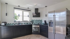 Una cocina moderna con armarios oscuros, un refrigerador de acero inoxidable y una ventana que proporciona luz natural.