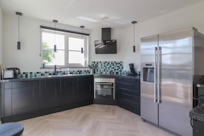 Eine moderne Küche mit dunklen Schränken, einem Edelstahlkühlschrank und einem Fenster, das für natürliches Licht sorgt.