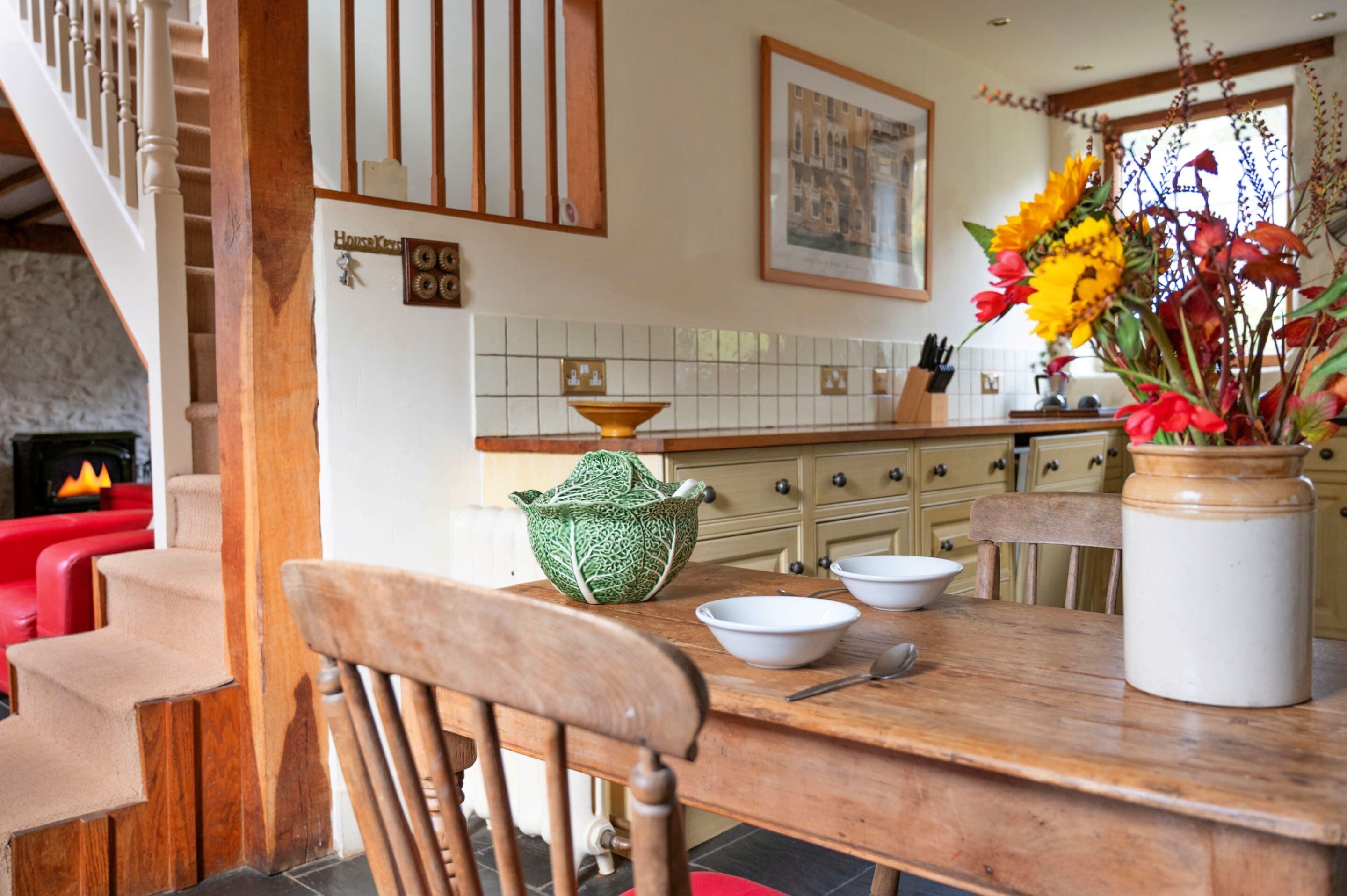 A dining area with a wooden table, chairs, and a vase with flowers.