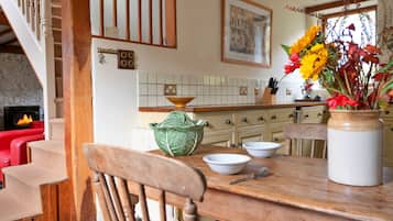 A dining area with a wooden table, chairs, and a vase with flowers.