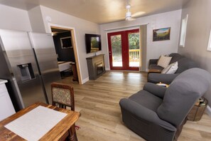 A modern living room with a sofa, a dining table, and a kitchen area with a refrigerator.