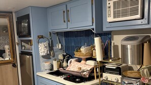 Una kitchenette compacta con microondas, tostadora y refrigerador.