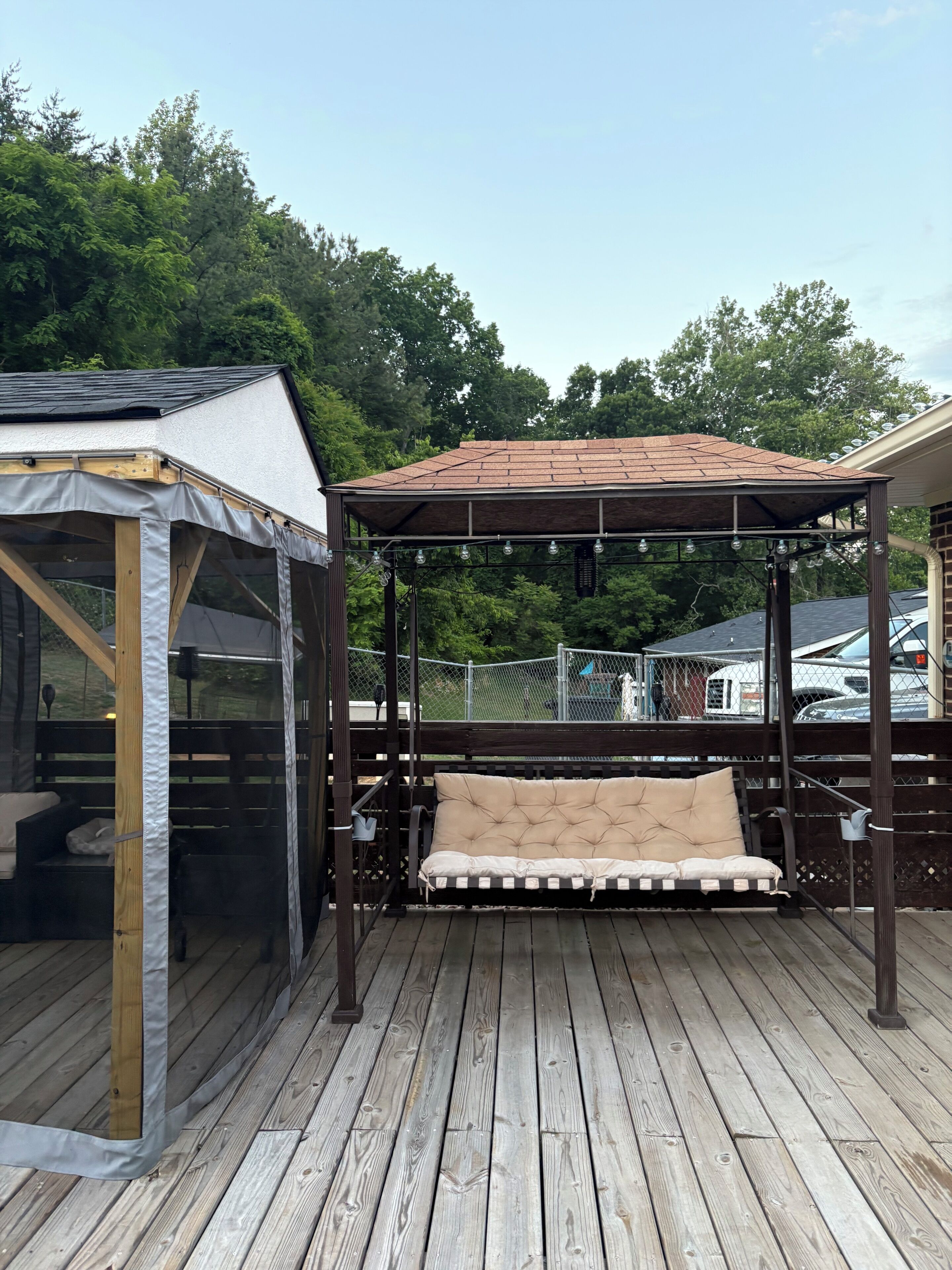 A wooden deck with a covered seating area and a small enclosed space.