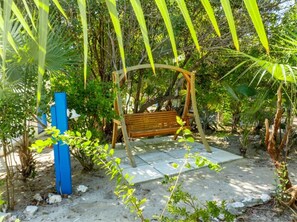 A wooden bench under a curved structure surrounded by greenery. - Turks & Caicos Retreat | 1BR Private | Experiences (Providenciales)