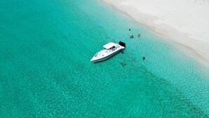 A boat anchored near a white sandy beach with clear turquoise water. - Turks & Caicos Retreat | 1BR Private | Experiences (Providenciales)